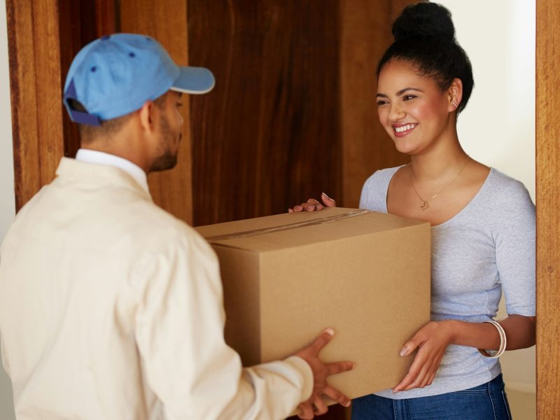 Shot of a delivery man making a delivery to a customer at her home